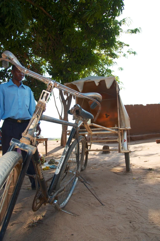 a man in a blue shirt standing beside some parked bicycles