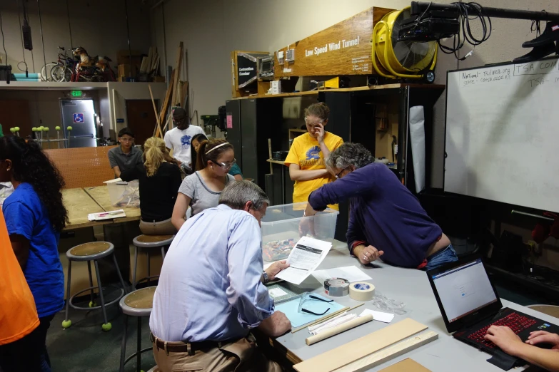 a group of people are gathered around a work space