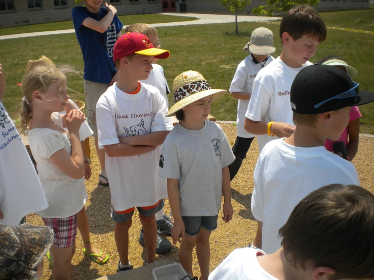 a group of boys and girls standing outside, one in front of the other