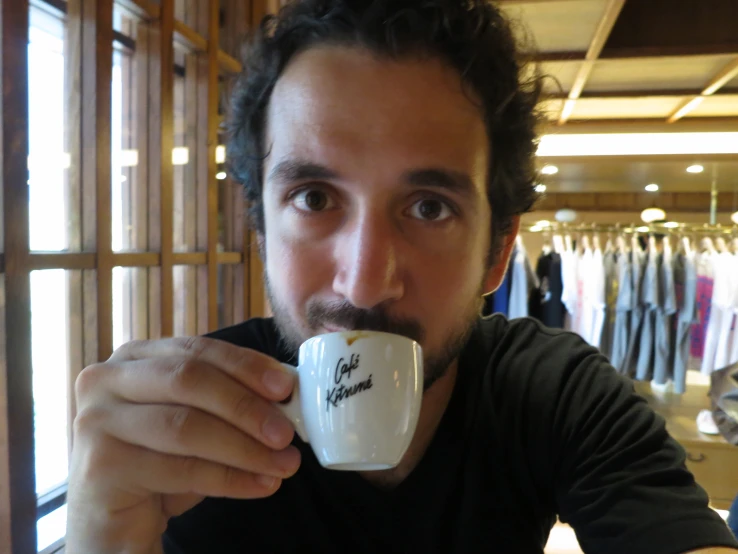 a man is holding up his coffee cup in a store