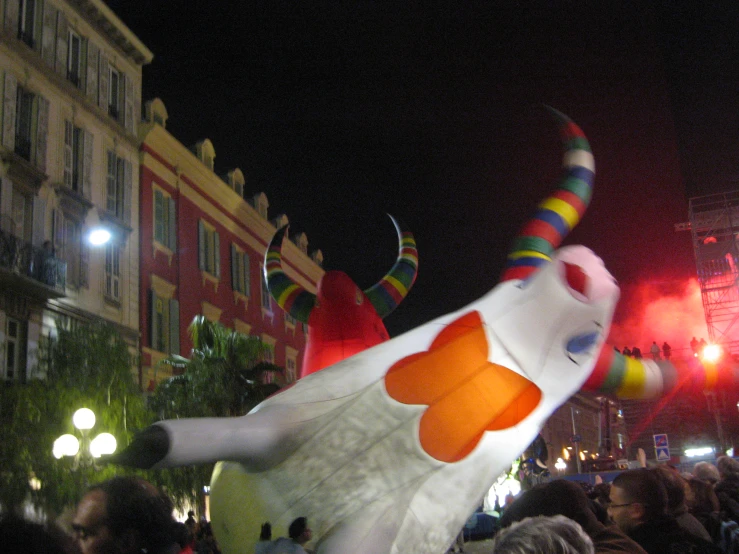 an inflatable costume depicting the face and hands of a fish is being held at night