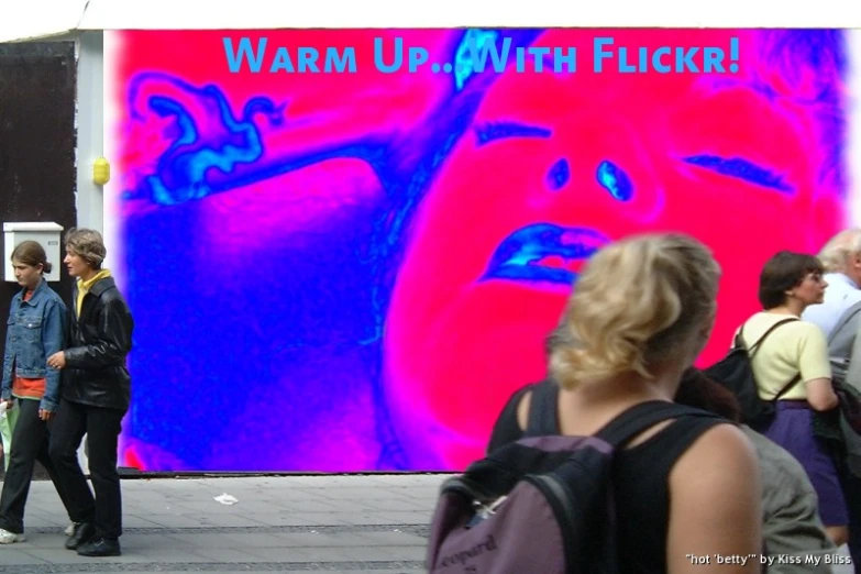 people walking past a large poster showing a man blowing his nose