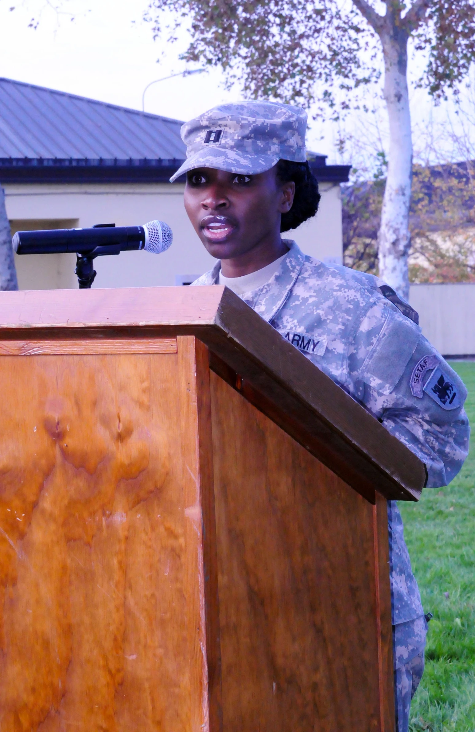 a woman standing at a podium in front of a microphone