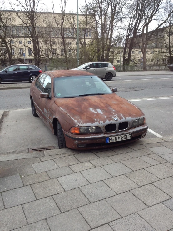 an old rusted out car parked next to a curb