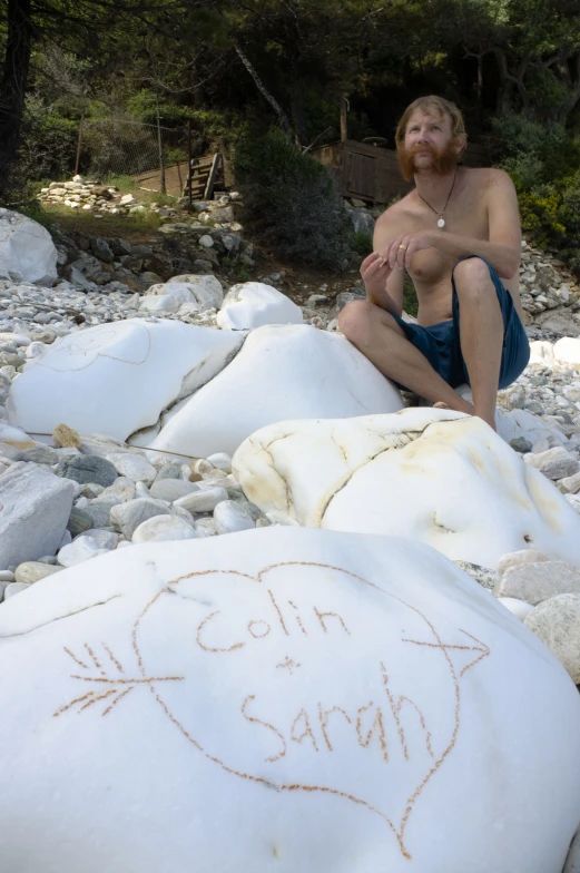 a man sitting on some large white rocks