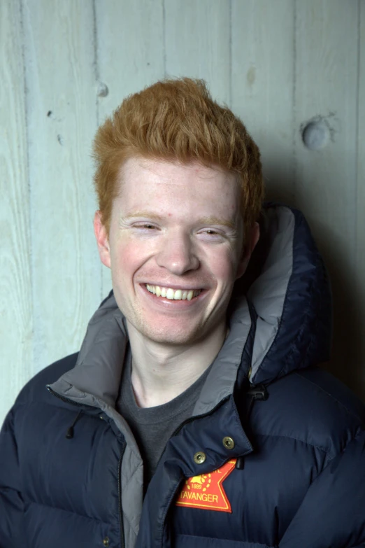 a young red headed man with red hair and jacket smiling