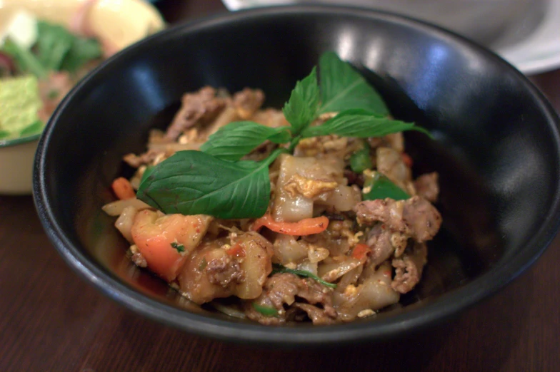 a black bowl on top of a table topped with food