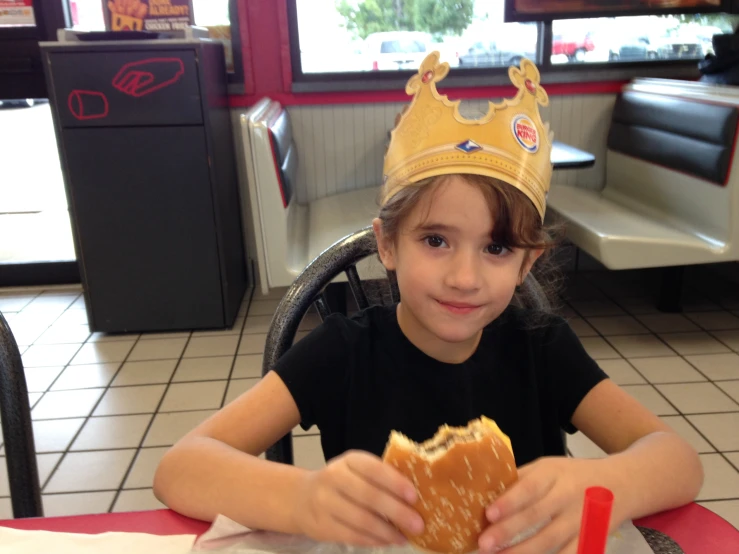 a child eating a pastry wearing a crown