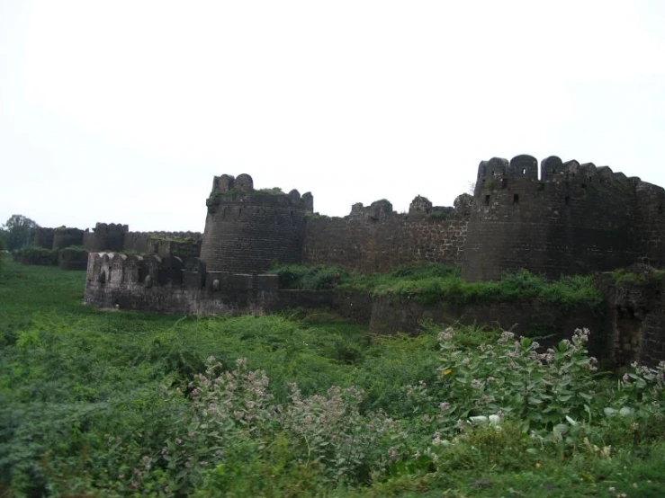 a large brick wall on a lush green hillside