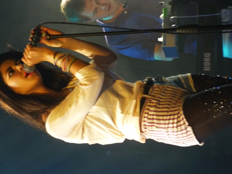 a woman with a microphone on stage in front of a piano