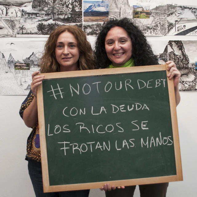 two girls hold a sign with spanish writing on it