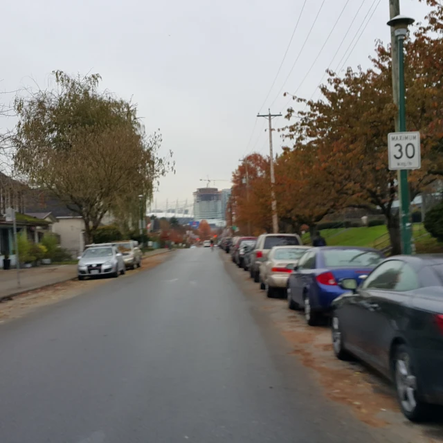 a street filled with lots of parked cars next to tall buildings