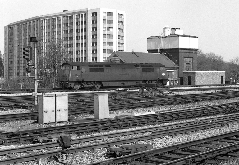 a train traveling down tracks next to a tall building