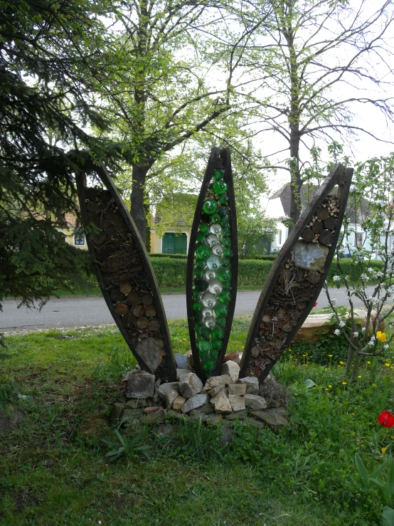 a sculpture on the side of a street that has several different leaves and stones