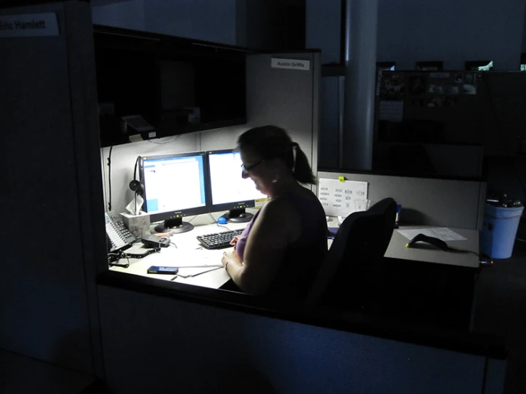 a person sitting at a desk with two computers