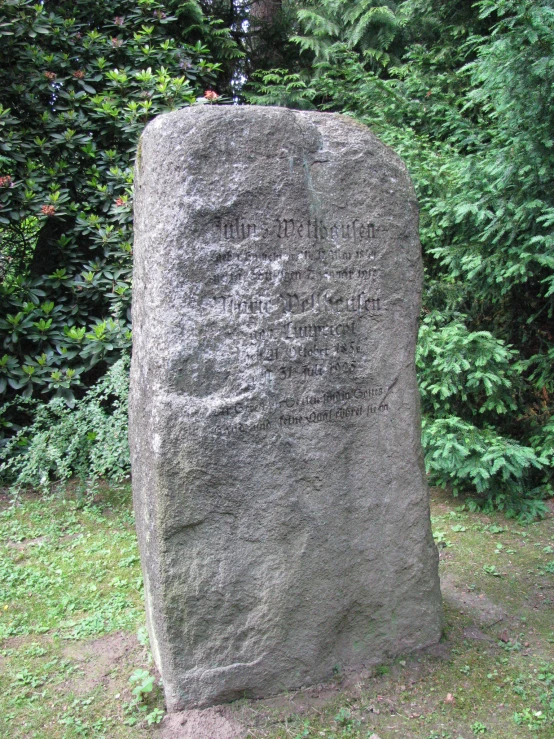 an intricate, gray, rock type monument with cursive writing on it