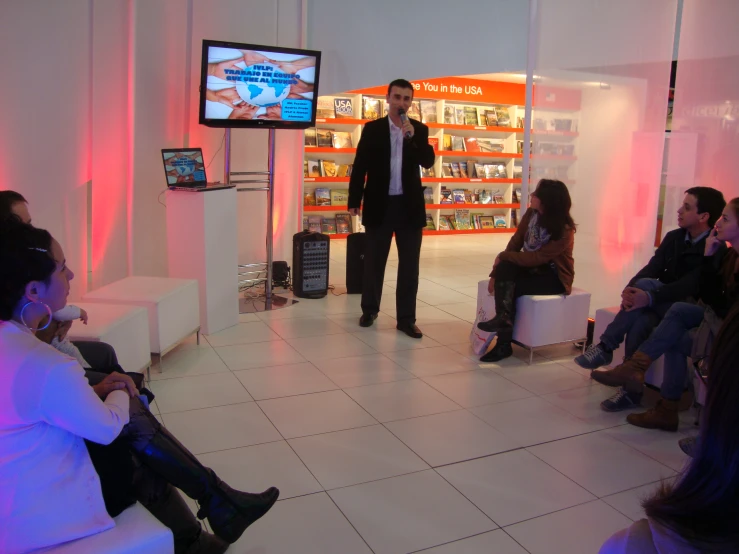 a man is standing near a woman with a cell phone and a large screen