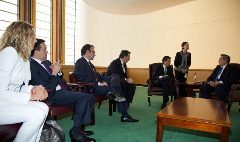 a group of people sitting around talking and being observed by three other people