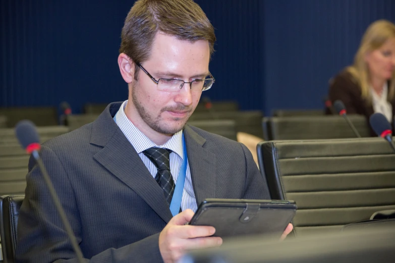 a man in a gray suit looking at his tablet