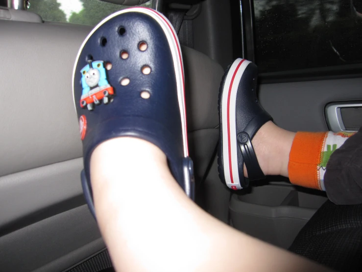 a child in blue slippers drives inside of a vehicle