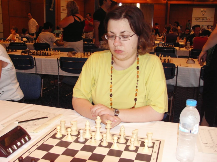a woman playing a game of checker board with many chess pieces