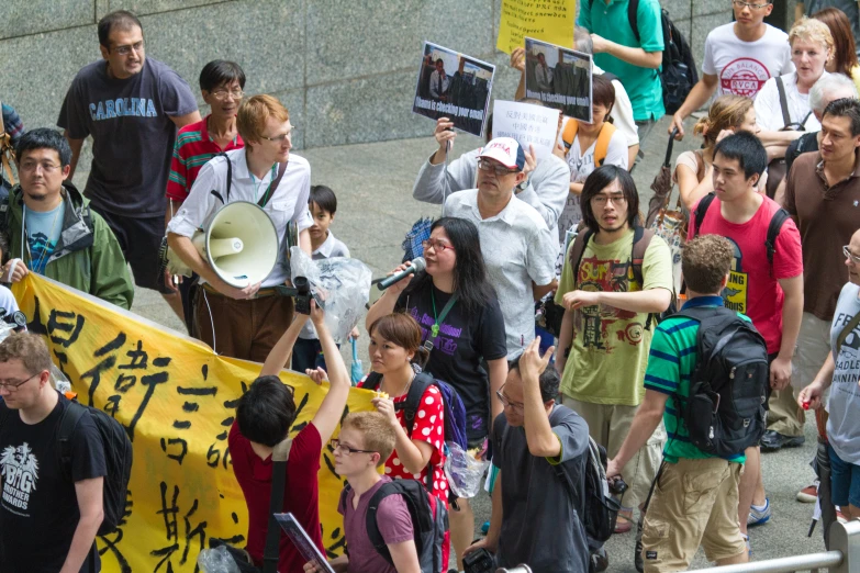 a crowd of people walking down the street with signs and loudphones