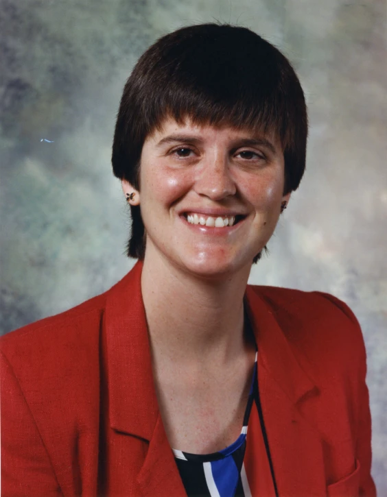 a woman with short hair and red jacket smiles