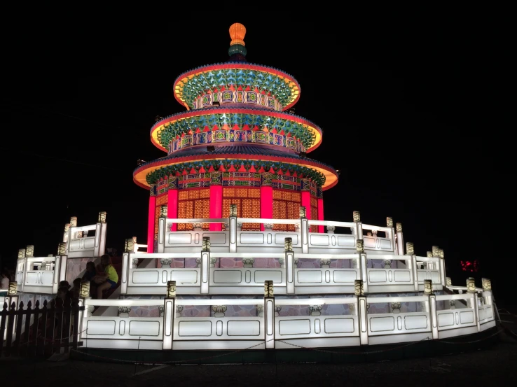 a chinese structure with a white fence and lights on it