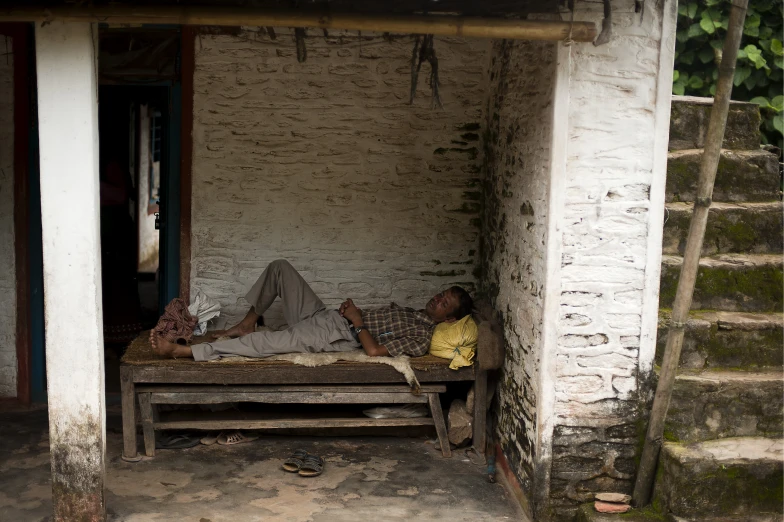 two people sleeping on top of a wooden bench