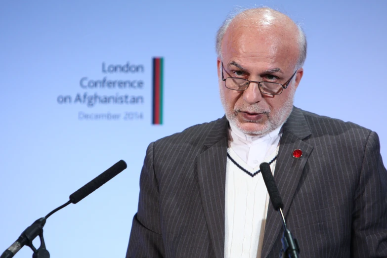 a man speaking in front of a microphone at a london conference on afghanism