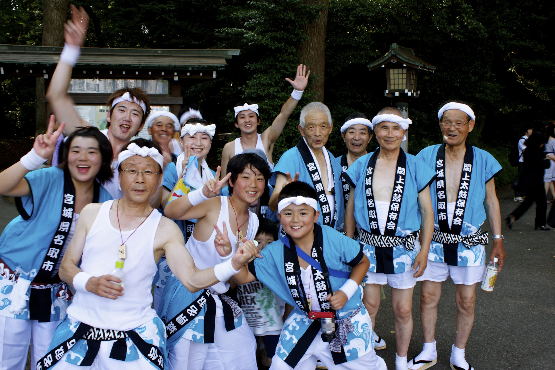 a group of asian men with sash ribbons and their hands up