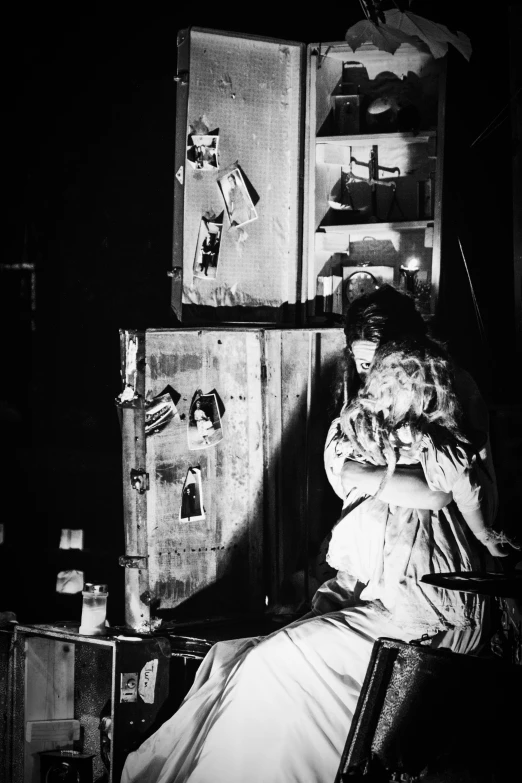 a woman in a dress sits in front of two old refrigerators