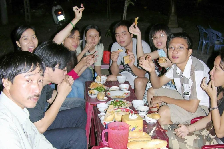 some people sitting on a table with food and drinks