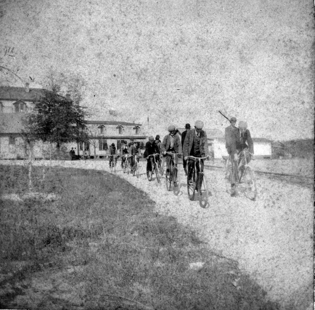 a group of people riding bicycles down a country road