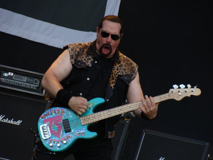 man in leopard print vest and glasses playing an electric guitar