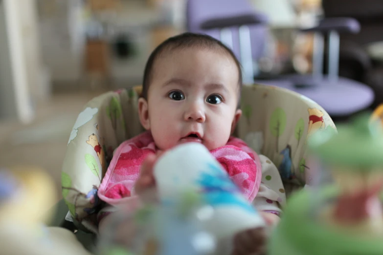 the small baby has her mouth open and is drinking out of a cup