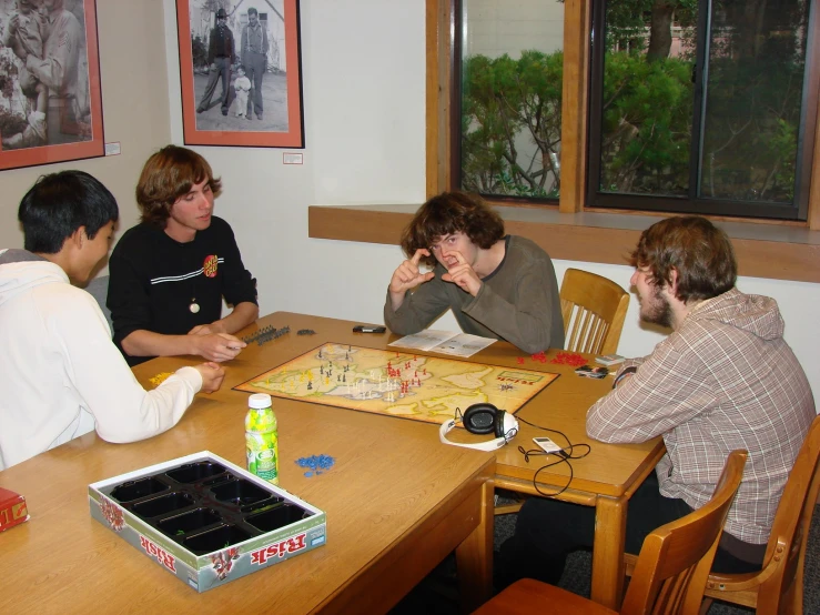 several young men playing a board game on a wooden table