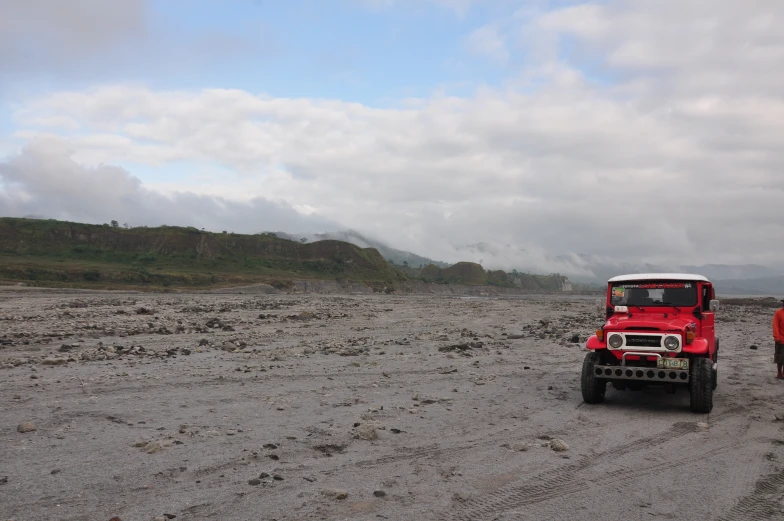 red jeep on rocky terrain with large mountains in distance