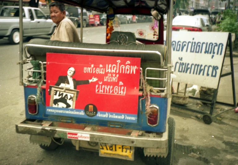 a man riding on the back of a blue and red bus