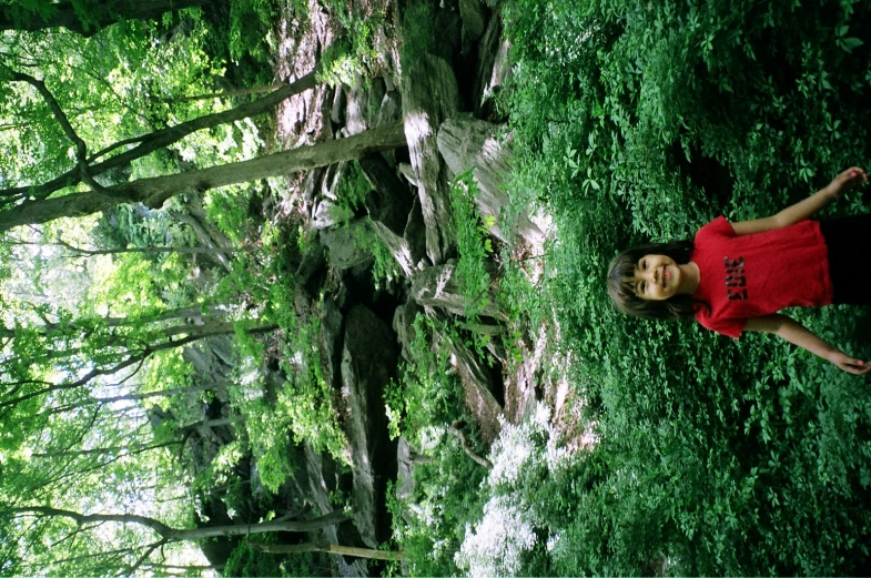 a girl standing in front of a big tree