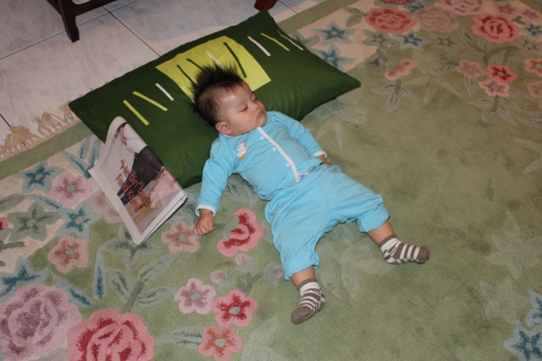 the small boy is lying on a floral area rug and enjoying the picture