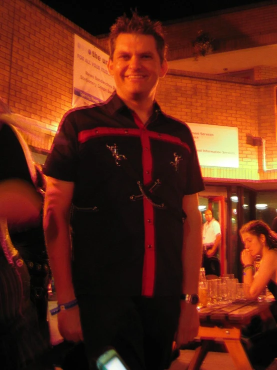 a man standing in a pub wearing a shirt with cross and skulls