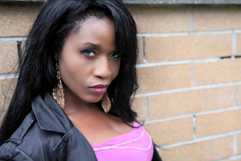 a woman with black hair standing against a wall