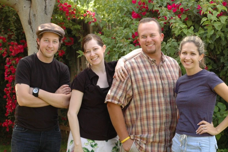 three men and two women standing in front of red roses