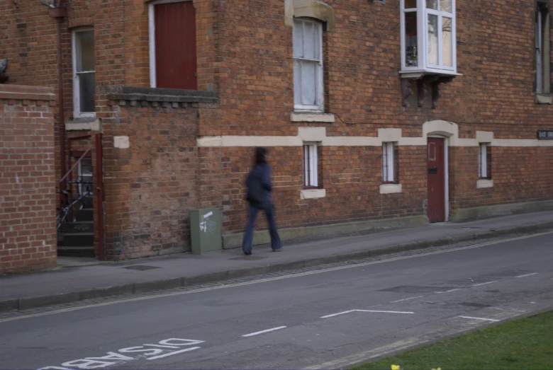 a person walking down the sidewalk near a building