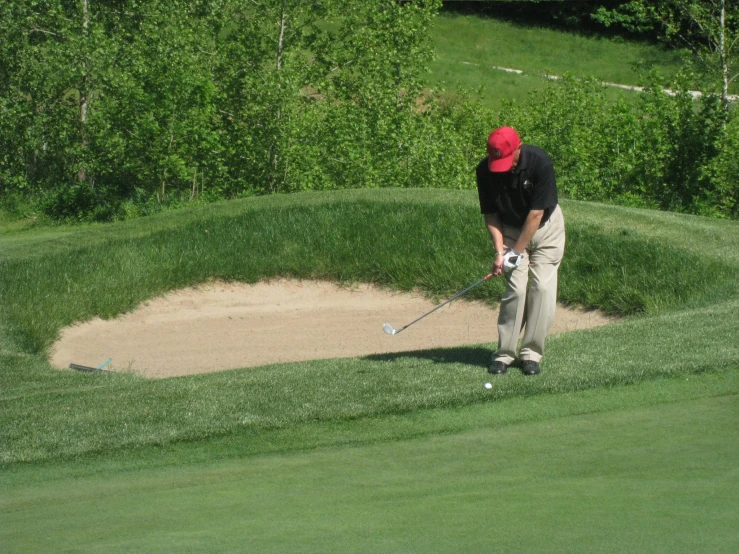 a man swings his golf club to hit a golf ball