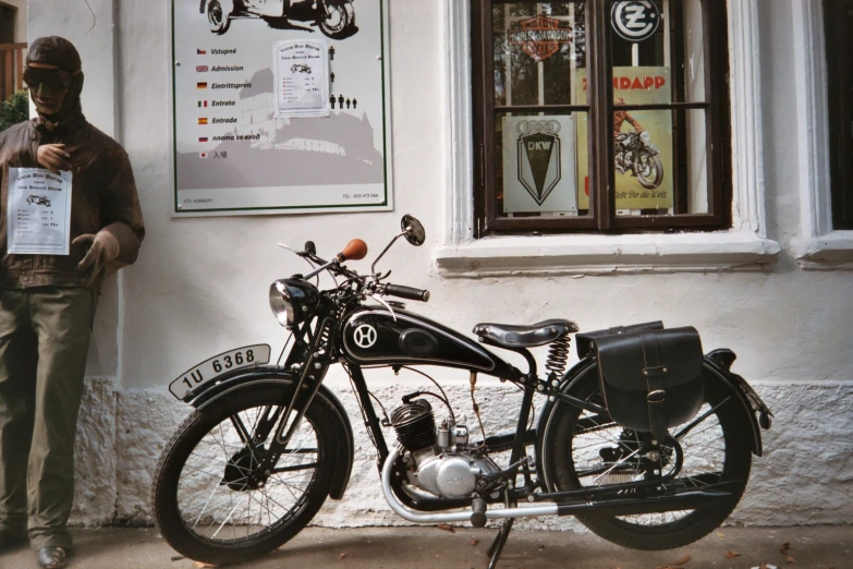 a man holds an autograph pass next to an old motorcycle