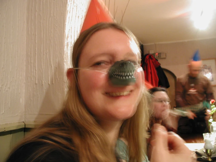 a smiling woman wearing a party hat while another woman looks on