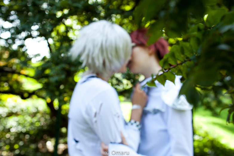 two young people with blond hair standing in front of trees