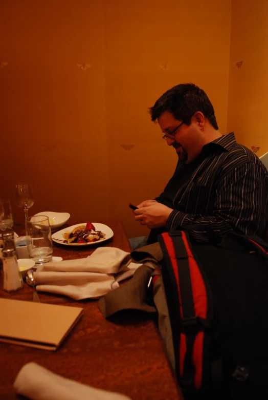 the man sits at a table using his cell phone